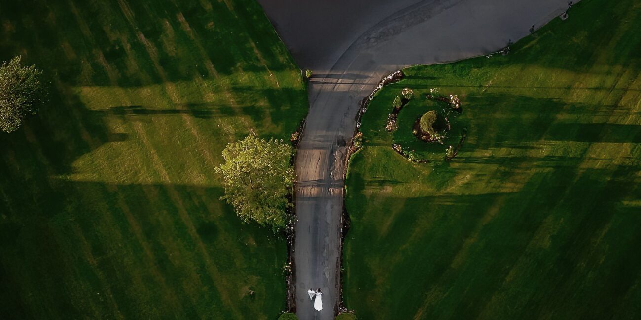 Drone image of a bride and groom walking to their venue